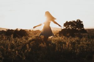 Menina andando no campo ao por do sol